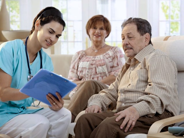 A nurese consulting an elderly couple in their home.