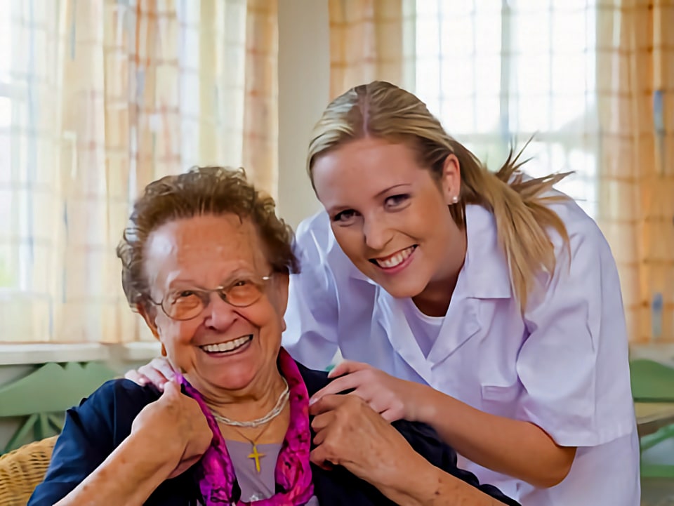 A nurse helping an elderly women in her home.